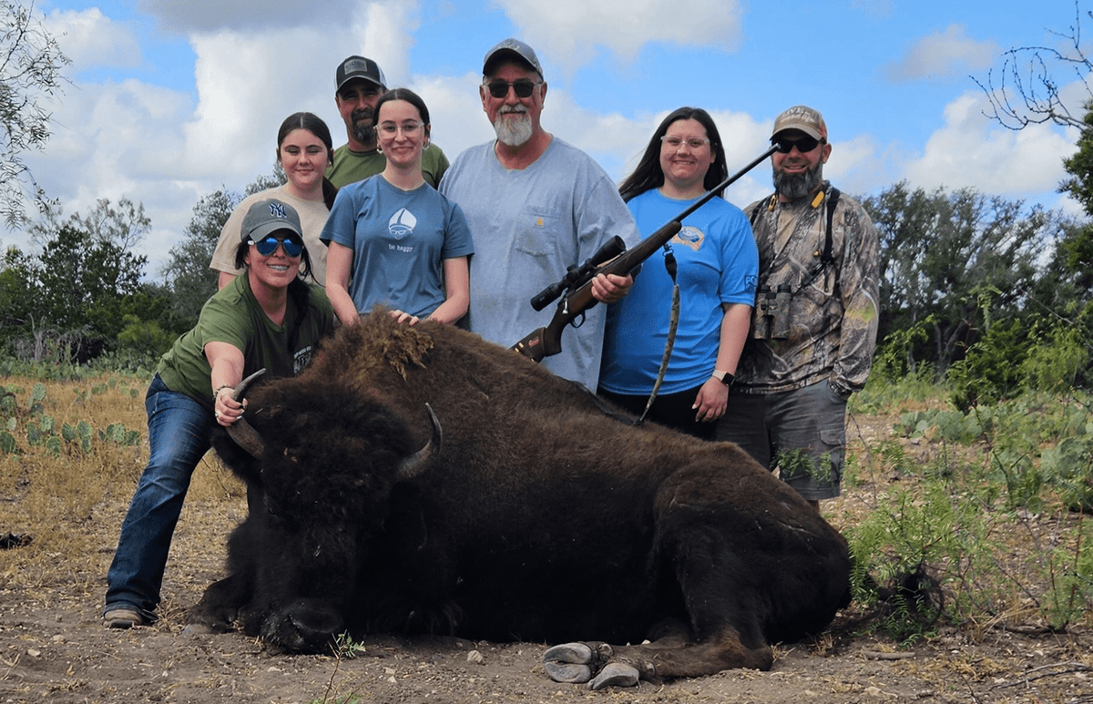 Group posing with a harvested bison in a clearing