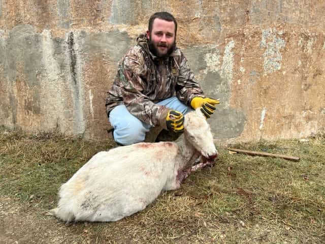 Hunter with a white goat beside a round tank