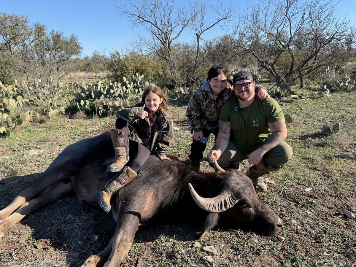 Group posing with a harvested buffalo in a clearing