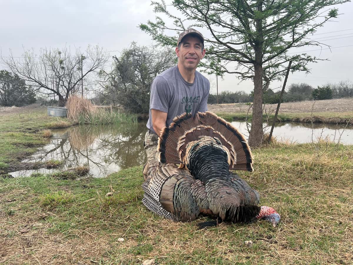 Hunter with a turkey beside a pond