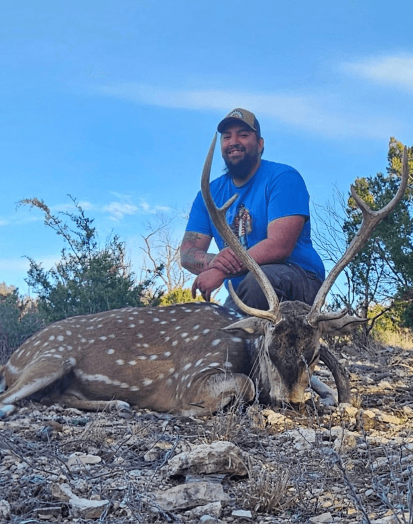 Hunter in a blue shirt with an Axis buck