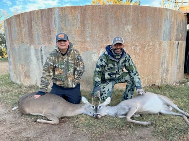 Two hunters with two deer beside a round tank