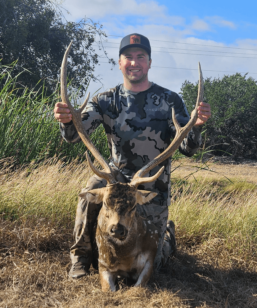 Hunter holding an Axis buck's antlers in sunlight