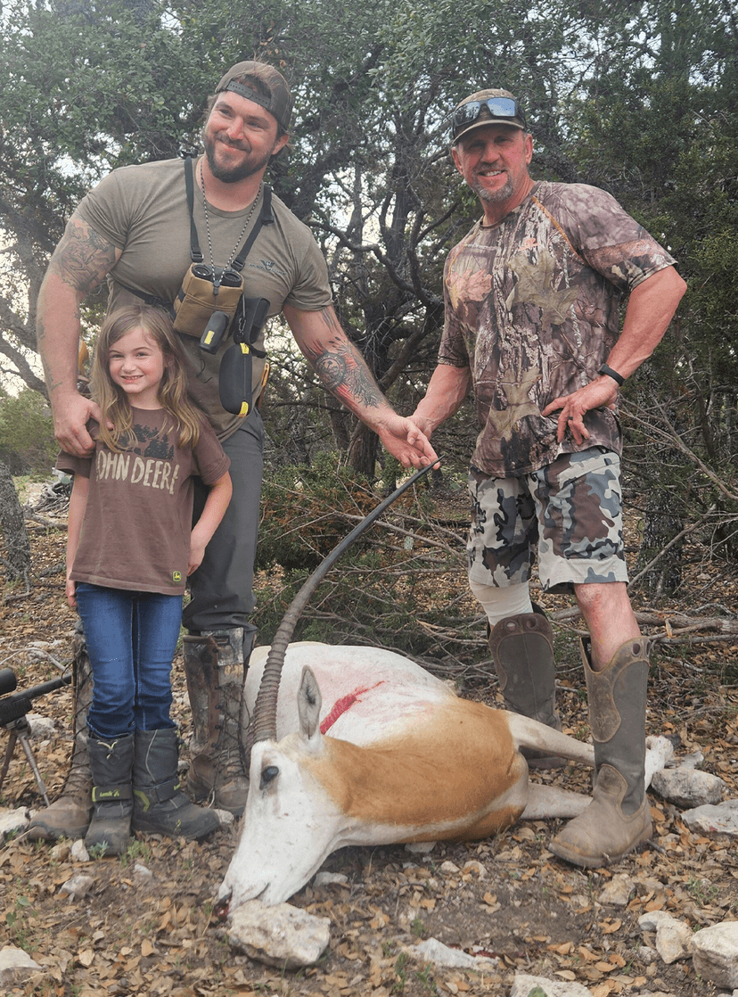 Three hunters with a white oryx beside trees