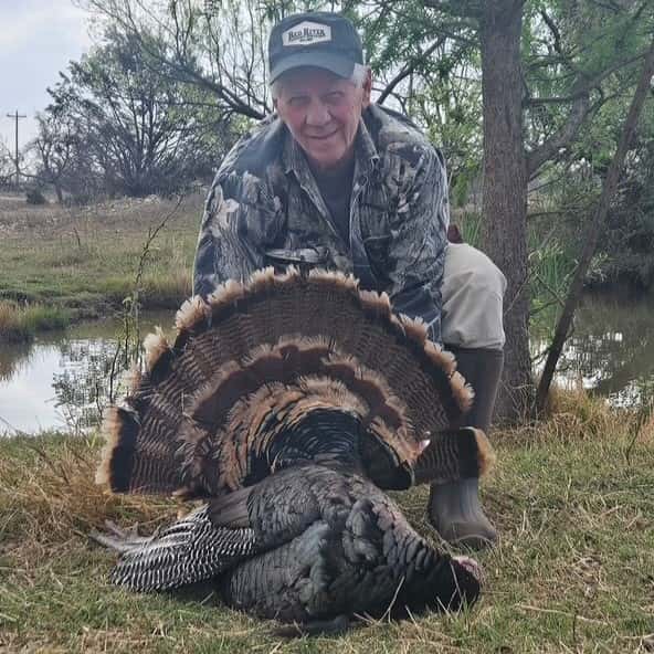 Hunter displaying a turkey beside a pond