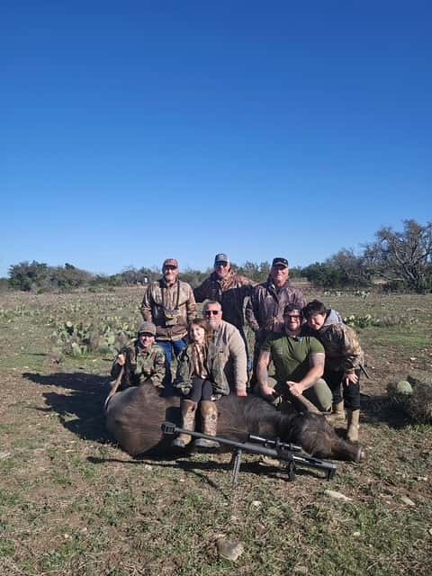 Group posing with a large harvested animal in a clearing