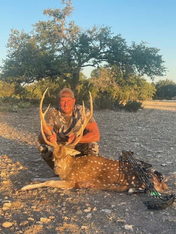 Hunter with an Axis buck in golden evening light