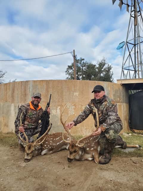 Two hunters with Axis bucks beside a round tank