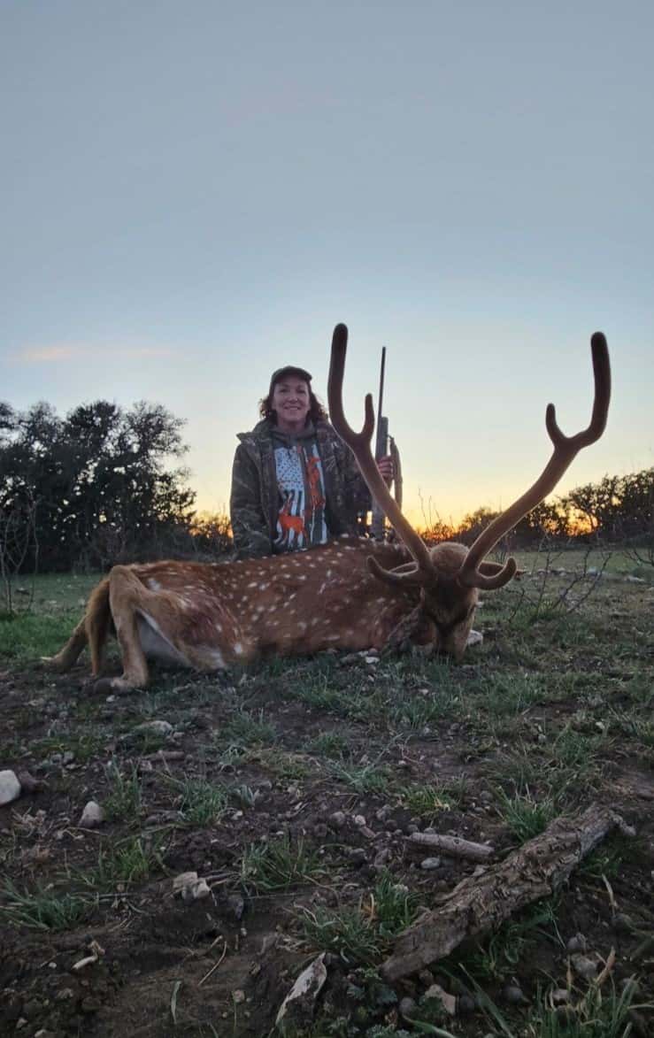 Hunter with an Axis buck at sunset