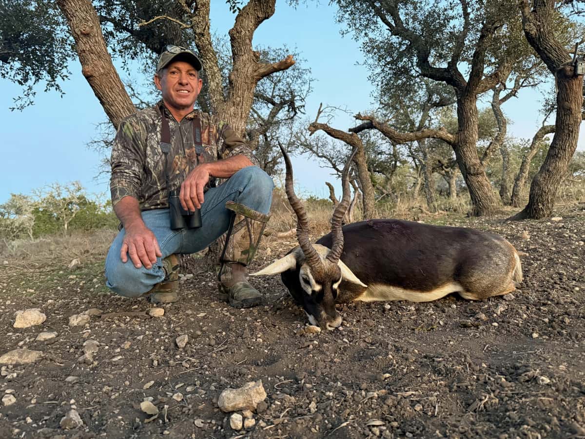 Hunter with a blackbuck antelope beneath a tree
