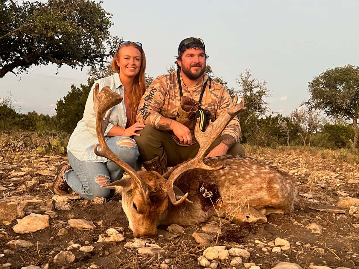 Two hunters with a fallow buck with broad antlers