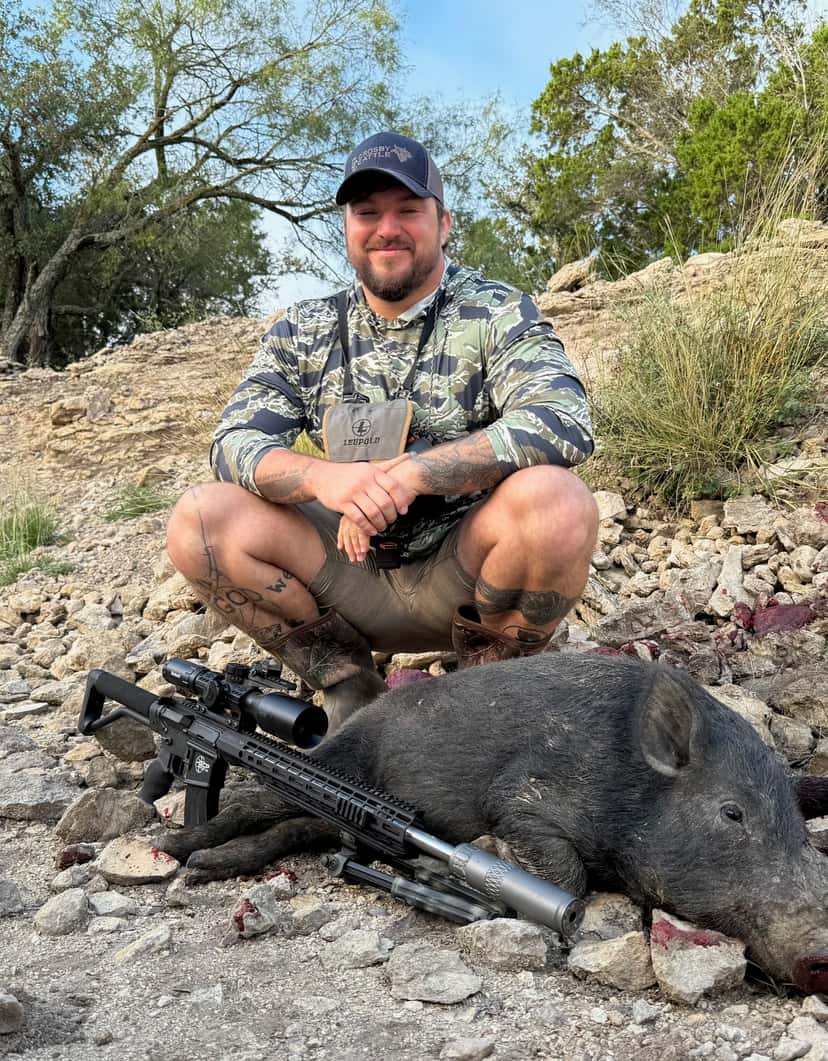 Hunter with a harvested hog on rocky ground