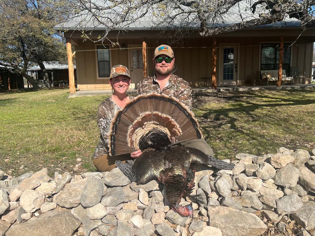 Two hunters displaying a turkey in front of the lodge