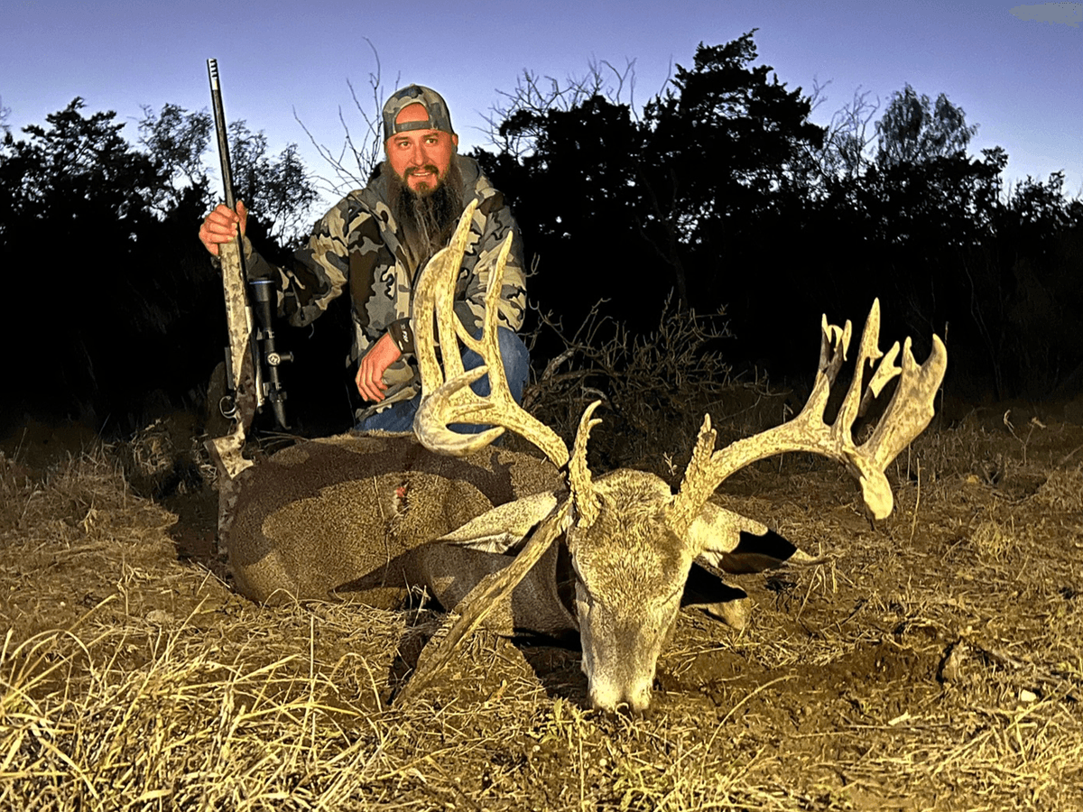 Hunter with a whitetail buck at dusk