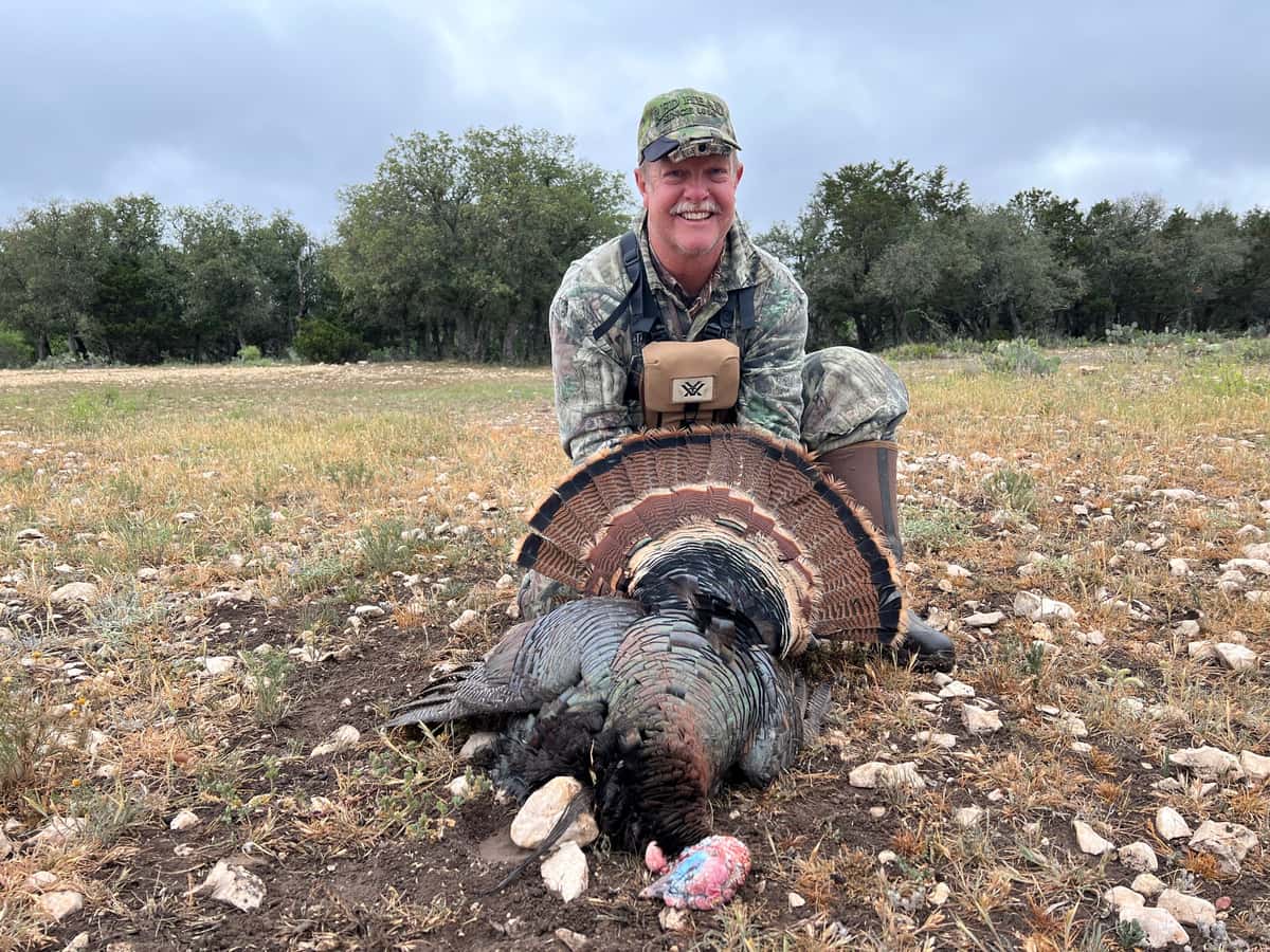 Hunter displaying a turkey in a rocky clearing
