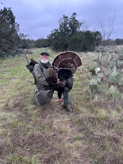 Hunter displaying a turkey beside cactus