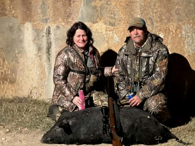 Two hunters with a black hog beside a round tank