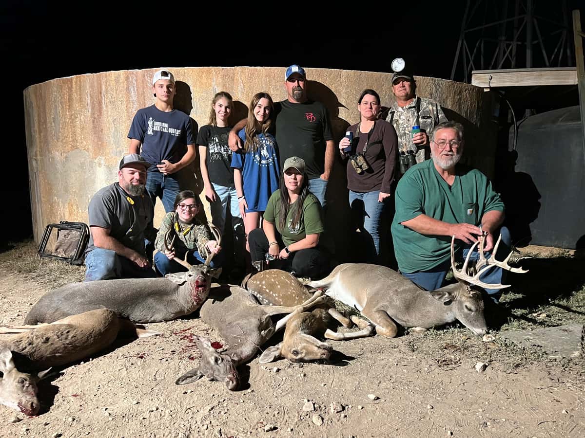 Group posing with several whitetail bucks at night