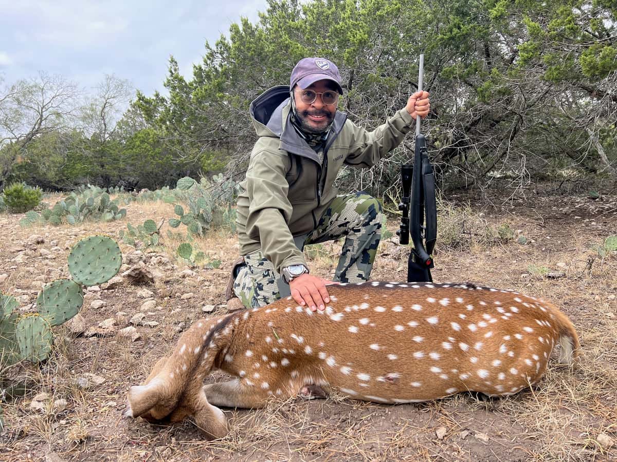 Hunter with an Axis deer beside cactus