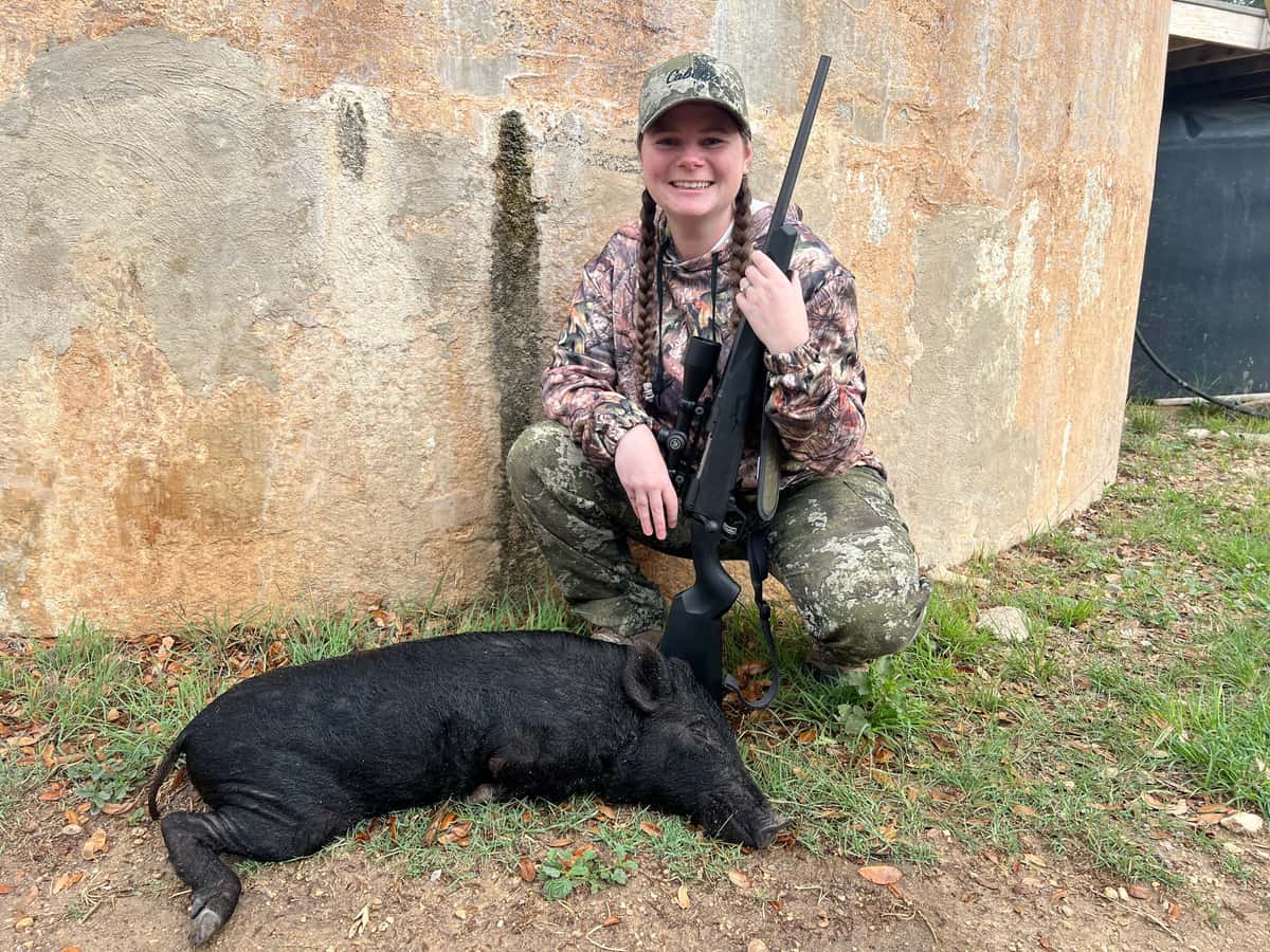 Hunter with a black hog beside a round tank