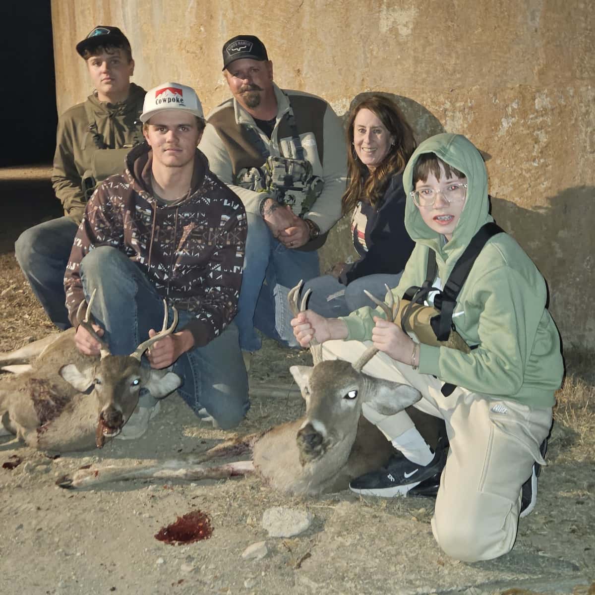 Group with whitetail bucks beside a round tank
