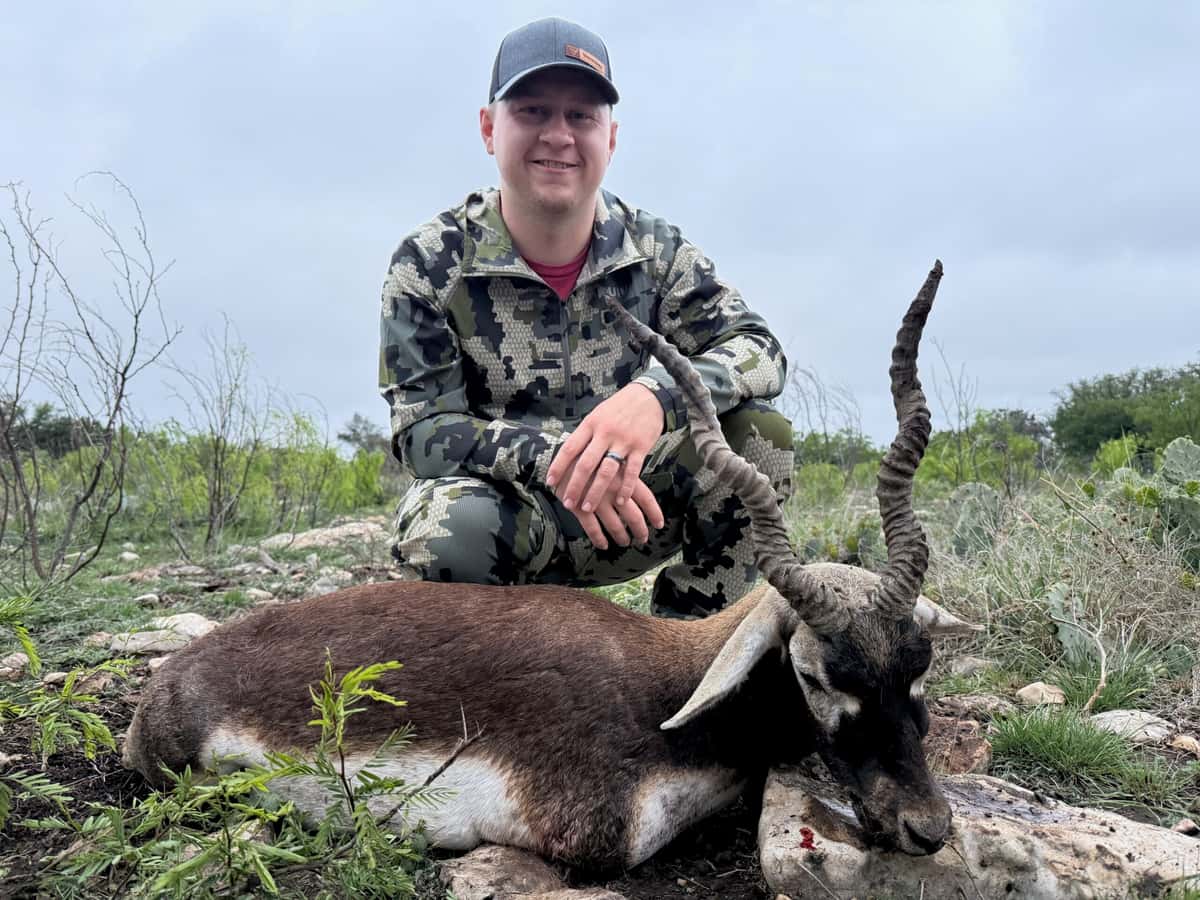 Hunter with a blackbuck antelope on rocky ground