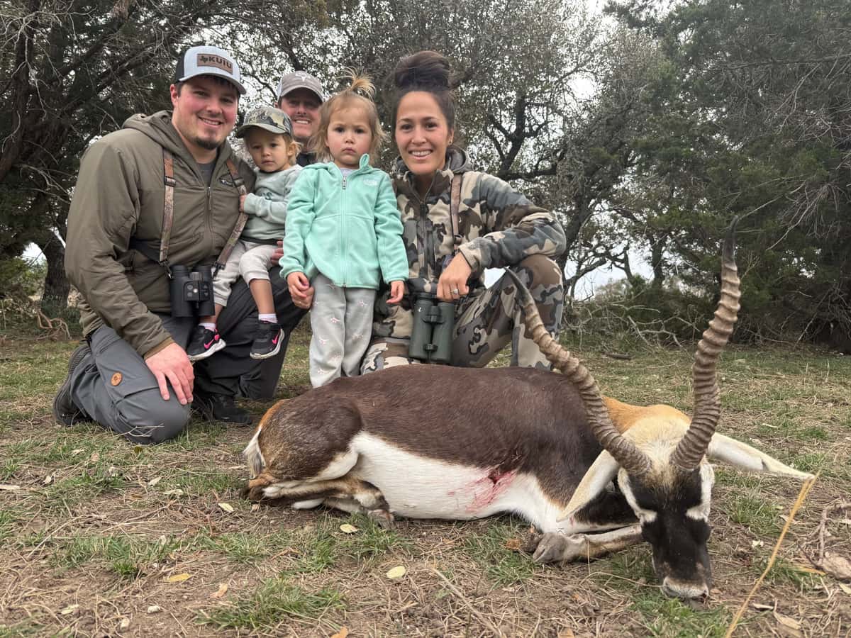 Group posing with a blackbuck antelope beneath trees