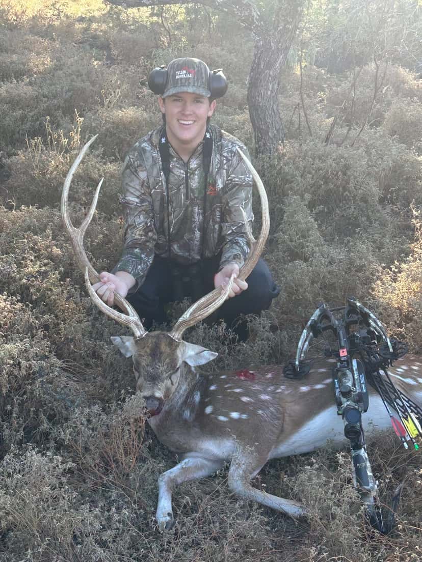 Bow hunter holding an Axis buck's antlers