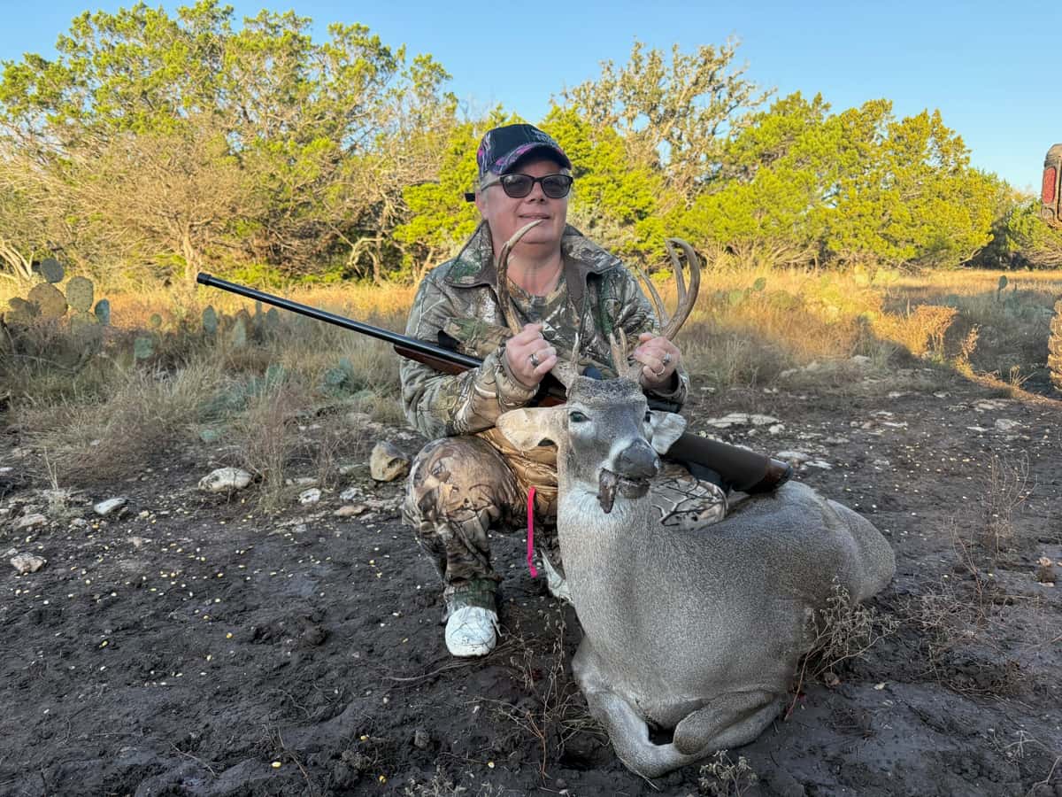 Hunter with a whitetail buck in afternoon sunlight