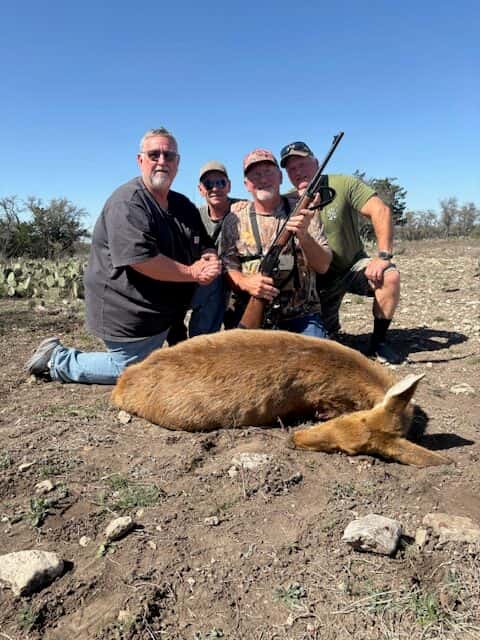 Group posing with a harvested hog on rocky ground