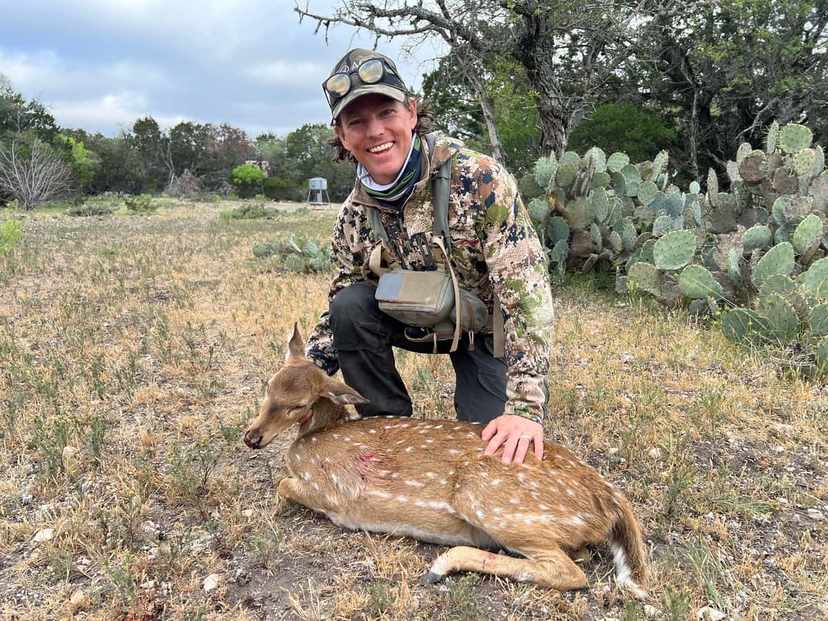 Hunter with an Axis doe beside cactus