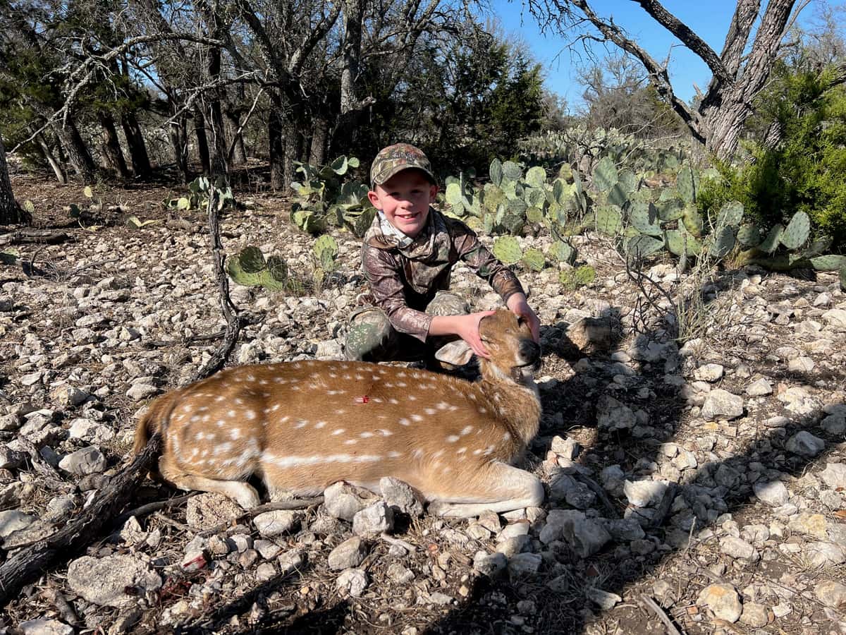 Hunter with an Axis deer beside cactus