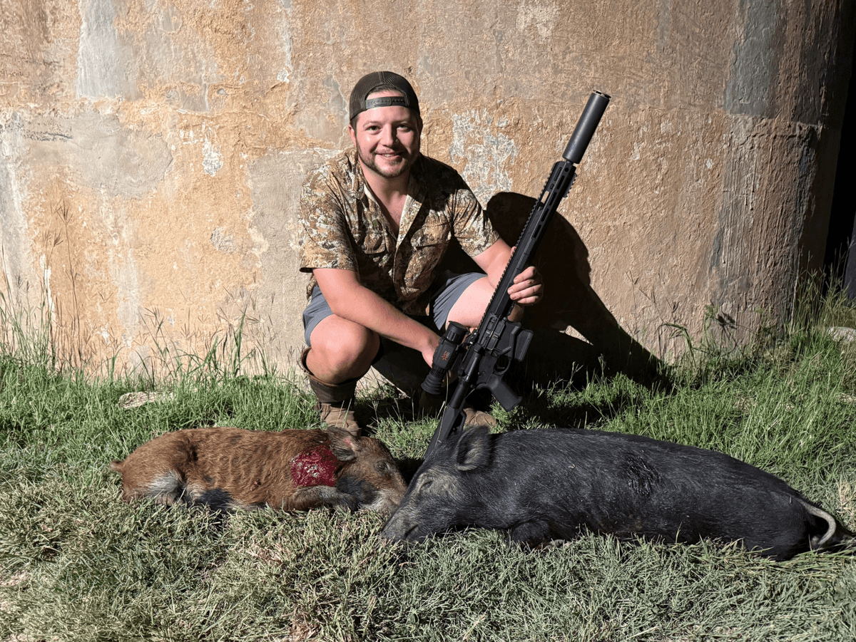 Hunter with harvested hogs beside a round tank