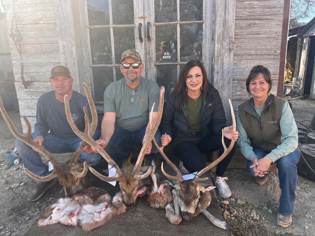 Group posing with several Axis bucks beside a ranch building