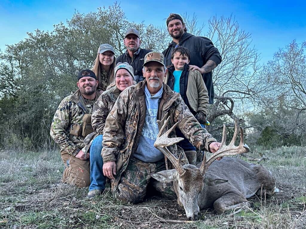 Group posing outdoors with whitetail bucks