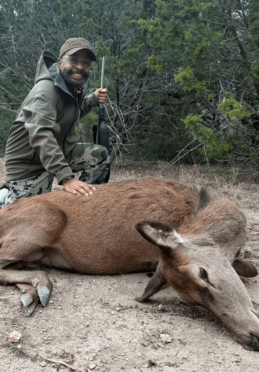 Hunter with a harvested hog beside brush