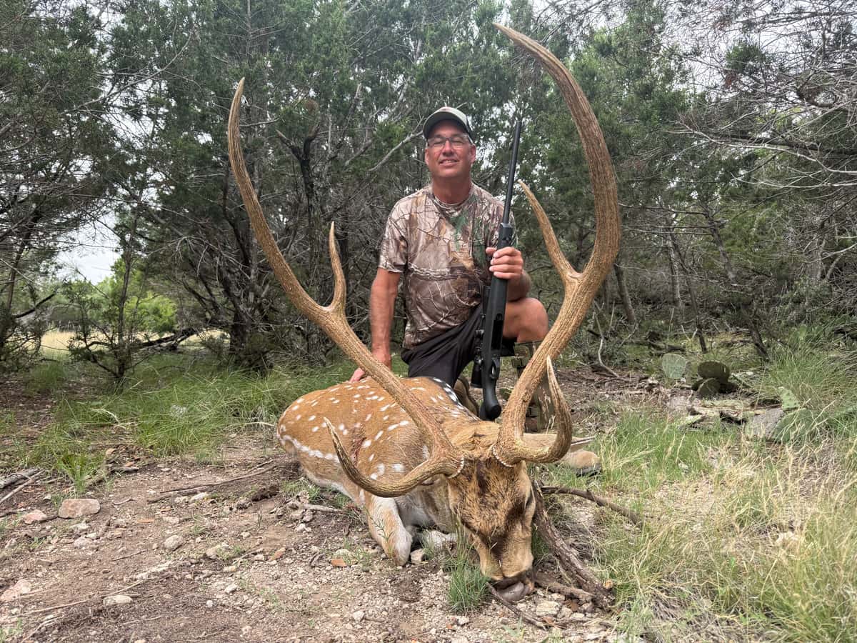 Axis hunter with a mature buck in cedar country at FF Hunting Ranch