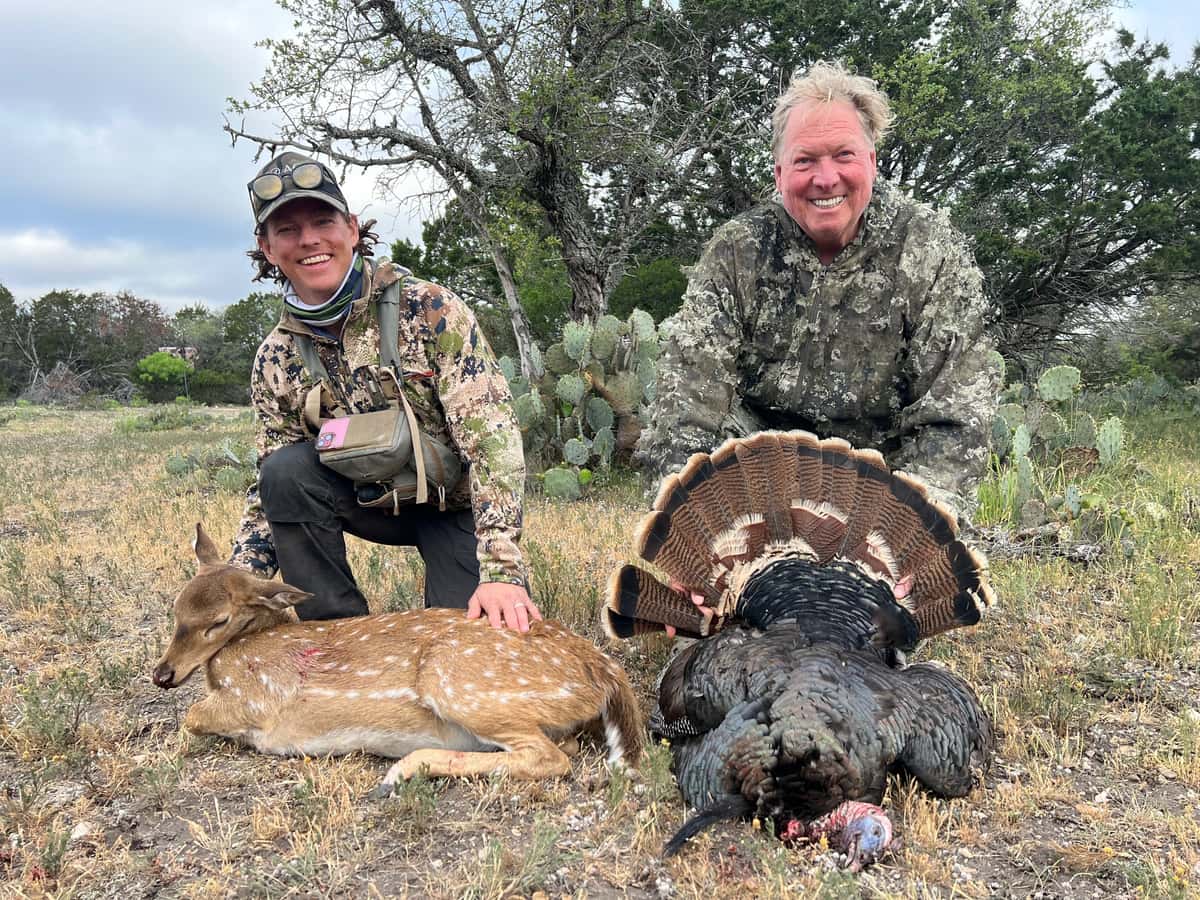 Two hunters with an Axis doe and a turkey